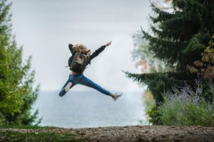 7 tips to feel better about your finances image shows happy woman jumping between trees